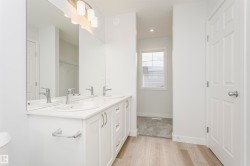 Double vanity with white cabinetry and chrome hardware, featuring dual undermount sinks and a wide mirror - 