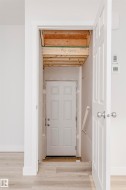 Light wood-finish flooring extending into an entry area with a white paneled door - 