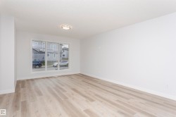 Spacious room featuring wood-finish flooring, white baseboards, and a large multi-pane window - 