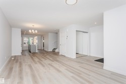 Open-concept living area featuring light wood-finish flooring, recessed lighting, and a modern chandelier - 