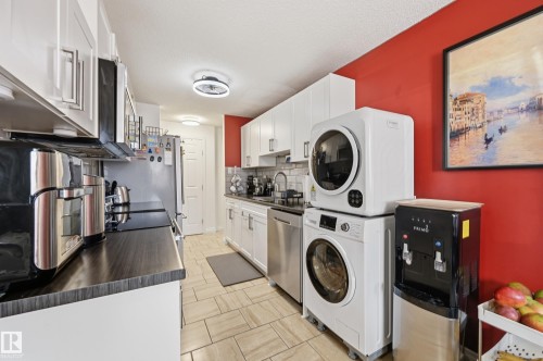 Compact kitchen featuring white cabinetry, dark wood-finish countertops, and stainless steel appliances - 105 7204 81 Avenue, Edmonton, AB - Indoor Photo Showing Laundry Room