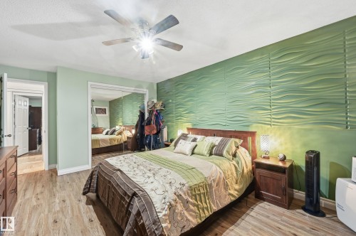 Bedroom featuring a textured accent wall, wood-finish flooring, and a ceiling fan with integrated lighting - 105 7204 81 Avenue, Edmonton, AB - Indoor Photo Showing Bedroom