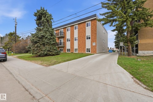 Three-story building with brick facade accents and light-colored siding, featuring multiple balconies with black railings - 105 7204 81 Avenue, Edmonton, AB - Outdoor