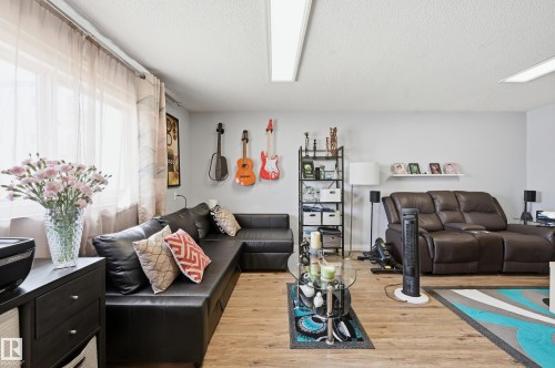 Spacious room featuring wood-finish flooring, light grey walls, and ample natural light from a large window - 105 7204 81 Avenue, Edmonton, AB - Indoor Photo Showing Living Room
