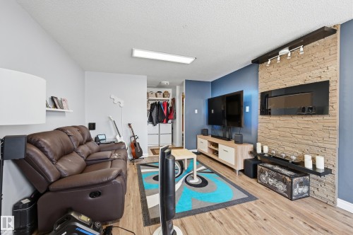 Feature wall with horizontal stacked stone detailing and an integrated linear fireplace - 105 7204 81 Avenue, Edmonton, AB - Indoor Photo Showing Living Room With Fireplace