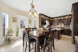Open-concept kitchen and dining area featuring dark wood cabinetry, granite countertops, and a mosaic tile backsplash - 