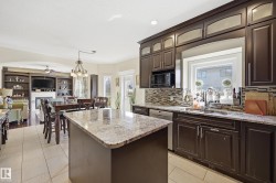 Kitchen featuring dark wood cabinetry, granite countertops, tile backsplash, and a large window above the sink - 