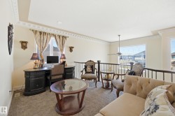 Open loft area featuring a window with exterior visibility, a ceiling fan, and decorative crown molding - 