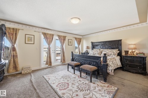 Spacious room featuring a tray ceiling with decorative crown molding, light-toned wall paint, and double French doors opening to an exterior - 3105 65 Street, Beaumont, AB - Indoor Photo Showing Bedroom