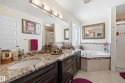 Bathroom featuring a dual vanity with granite countertops, integrated sinks, and dark wood cabinetry - 