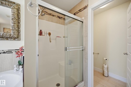 Shower enclosure featuring clear glass sliding doors and a built-in shower niche - 3105 65 Street, Beaumont, AB - Indoor Photo Showing Bathroom