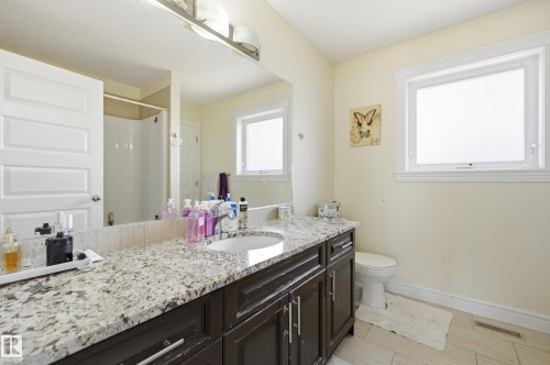 Bathroom featuring a dark wood-finish vanity with ample storage, a granite countertop, and an undermount sink - 3105 65 Street, Beaumont, AB - Indoor Photo Showing Bathroom