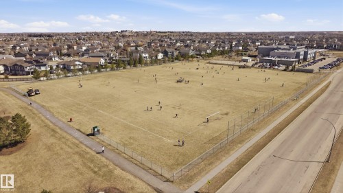 Expansive outdoor recreational field bordered by residential properties and a paved road - 3105 65 Street, Beaumont, AB - Outdoor With View