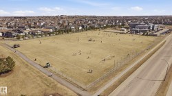 Expansive outdoor recreational field bordered by residential properties and a paved road - 