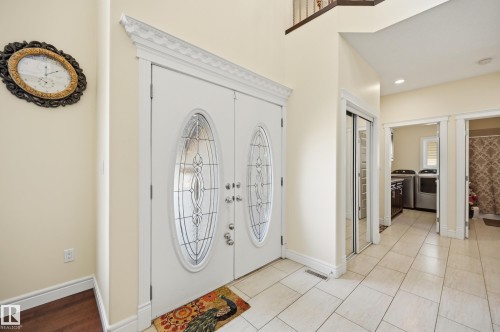 Foyer featuring a double entry door with decorative glass inserts, crown molding, tile flooring, and a mirrored closet door - 3105 65 Street, Beaumont, AB - Indoor Photo Showing Other Room