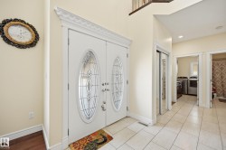 Foyer featuring a double entry door with decorative glass inserts, crown molding, tile flooring, and a mirrored closet door - 