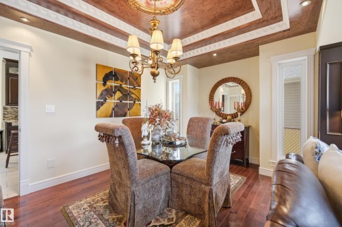 Tray ceiling with decorative molding and recessed lighting, brass chandelier, wood-finish flooring, and white baseboards - 3105 65 Street, Beaumont, AB - Indoor Photo Showing Dining Room