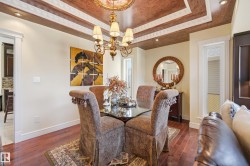 Tray ceiling with decorative molding and recessed lighting, brass chandelier, wood-finish flooring, and white baseboards - 