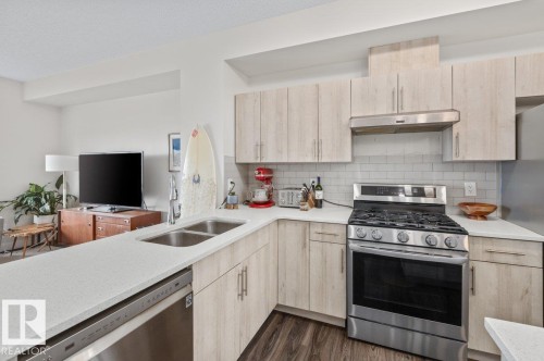 Contemporary kitchen featuring light wood-finish cabinetry, stainless steel appliances, white countertops, and a subway tile backsplash - 21 979 Crystallina Nera Way, Edmonton, AB - Indoor Photo Showing Kitchen With Double Sink