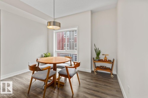 Recessed dining area featuring dark wood-finish flooring, a contemporary pendant light fixture, a large window, white baseboards, and neutral wall tones - 21 979 Crystallina Nera Way, Edmonton, AB - Indoor Photo Showing Dining Room