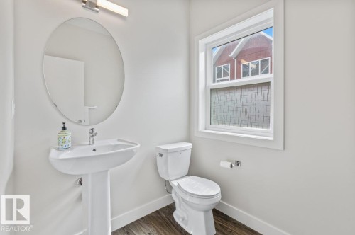 Pedestal sink with a chrome faucet, oval mirror, and a linear vanity light fixture - 21 979 Crystallina Nera Way, Edmonton, AB - Indoor Photo Showing Bathroom