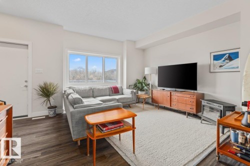 Living area featuring wood-finish flooring, white walls, and a large multi-pane window - 21 979 Crystallina Nera Way, Edmonton, AB - Indoor Photo Showing Living Room