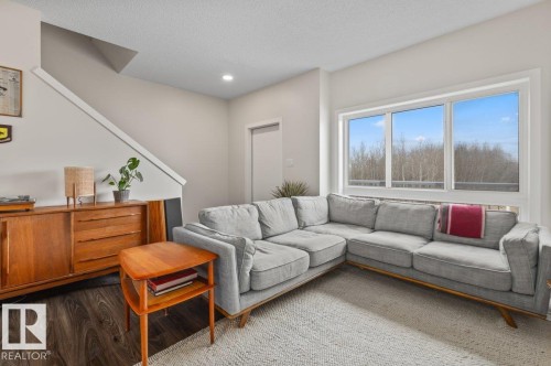 Bright living area featuring a large multi-pane window, recessed lighting, and wood-finish flooring - 21 979 Crystallina Nera Way, Edmonton, AB - Indoor Photo Showing Living Room