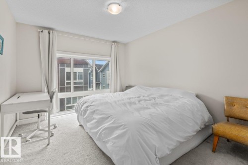 Bedroom featuring a large window, light gray carpet, and neutral wall tones - 21 979 Crystallina Nera Way, Edmonton, AB - Indoor Photo Showing Bedroom