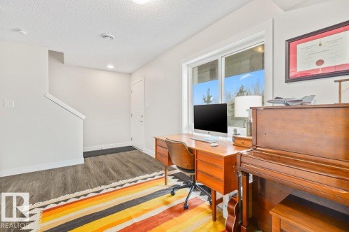 Spacious room with large windows, wood-finish flooring, a contemporary stairway, and bright overhead lighting - 21 979 Crystallina Nera Way, Edmonton, AB - Indoor Photo Showing Office