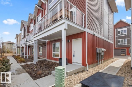 Multi-level townhouse exterior featuring red siding and white trim - 21 979 Crystallina Nera Way, Edmonton, AB - Outdoor With Balcony