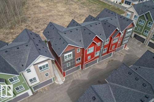 Modern townhome complex featuring multi-toned siding, dark gray shingle roofing, and integrated garages - 21 979 Crystallina Nera Way, Edmonton, AB - Outdoor