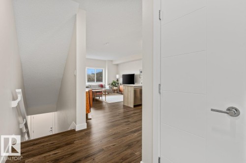 Entryway featuring wood-finish flooring, a contemporary white interior door with horizontal paneling and polished chrome hardware - 21 979 Crystallina Nera Way, Edmonton, AB - Indoor Photo Showing Other Room