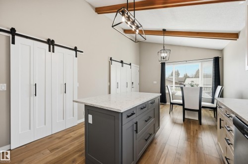 Kitchen featuring a center island with a light-toned countertop, wood-finish flooring, exposed wood ceiling beams, and barn-door style closet doors - 1729 65 Street, Edmonton, AB - Indoor Photo Showing Kitchen