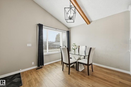 Dining area featuring wood-finish flooring, a vaulted ceiling with an exposed beam, and a contemporary black geometric chandelier - 1729 65 Street, Edmonton, AB - Indoor Photo Showing Dining Room