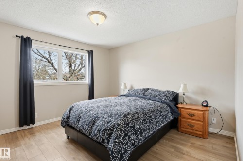 Bedroom featuring light wood-finish flooring, neutral wall paint, and a large window with white trim - 1729 65 Street, Edmonton, AB - Indoor Photo Showing Bedroom