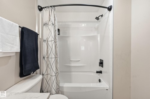 White bathtub and shower combination with matte black fixtures - 1729 65 Street, Edmonton, AB - Indoor Photo Showing Bathroom