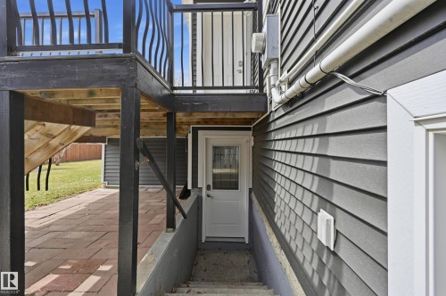 Side exterior access with a white door featuring a window panel, set against gray siding - 1729 65 Street, Edmonton, AB - Outdoor With Exterior