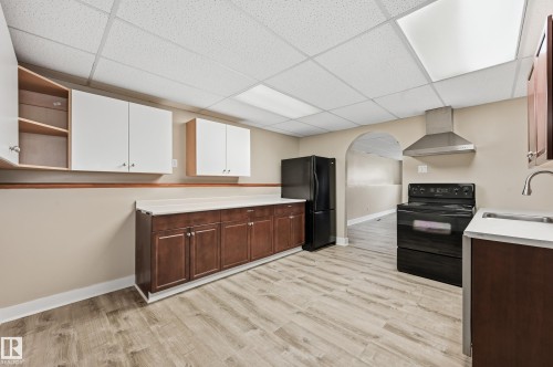 Kitchen featuring wood-finish flooring, two-tone cabinetry, and an arched doorway - 1729 65 Street, Edmonton, AB - Indoor Photo Showing Kitchen