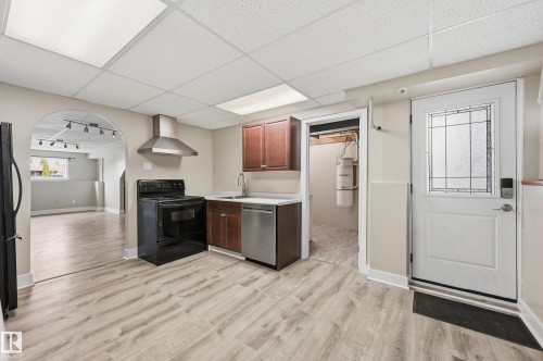 Kitchen space featuring wood-finish flooring, stainless steel appliances, dark wood cabinetry, and a stainless steel range hood - 1729 65 Street, Edmonton, AB - Indoor Photo Showing Kitchen