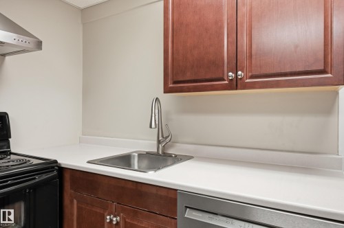 Kitchen space featuring wood-finish cabinetry, a stainless steel sink with a high-arc faucet, and white countertops - 1729 65 Street, Edmonton, AB - Indoor Photo Showing Kitchen