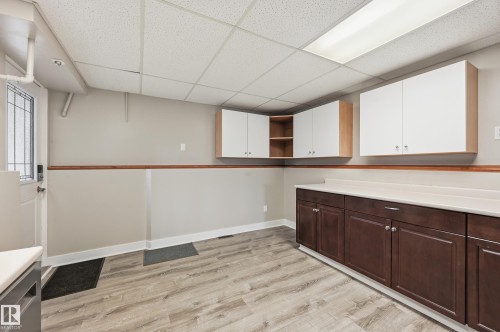 Utility room featuring wood-finish flooring, two-tone cabinetry with white upper and dark wood-finish lower units, and a drop ceiling with integrated lighting - 1729 65 Street, Edmonton, AB - Indoor