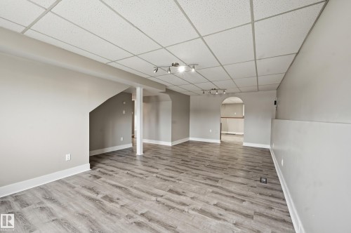 Spacious room featuring wood-finish flooring, light gray walls with white baseboards, and a drop ceiling with integrated track lighting - 1729 65 Street, Edmonton, AB - Indoor Photo Showing Other Room