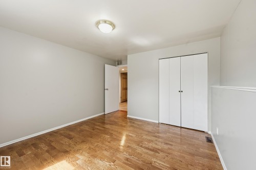 Room featuring wood-finish flooring, light gray walls, a ceiling-mounted light fixture, and a bi-fold closet - 1729 65 Street, Edmonton, AB - Indoor Photo Showing Other Room