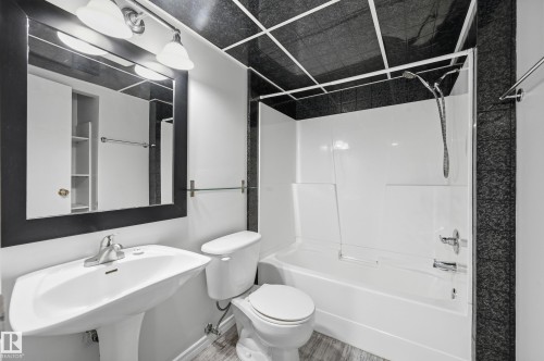 Bathroom featuring a pedestal sink, white toilet, and a combination tub/shower with a white surround - 1729 65 Street, Edmonton, AB - Indoor Photo Showing Bathroom