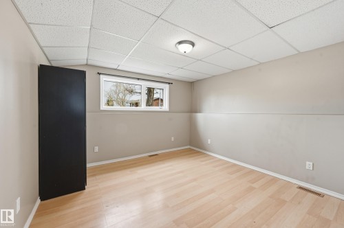 Spacious room featuring light wood-finish flooring, neutral paint, a drop ceiling, and a single window offering exterior visibility - 1729 65 Street, Edmonton, AB - Indoor Photo Showing Other Room