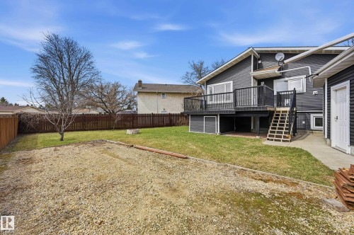Rear exterior featuring dark gray siding, a wood deck with black railing, and a concrete patio below - 1729 65 Street, Edmonton, AB - Outdoor With Deck Patio Veranda
