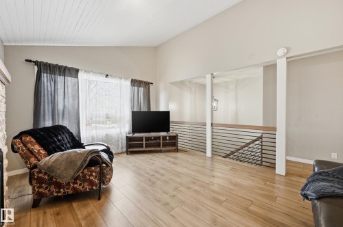 Spacious living area featuring high vaulted ceilings with wood-plank finishing, wood-finish flooring, and a stone-faced fireplace surround - 1729 65 Street, Edmonton, AB - Indoor