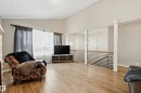 Spacious living area featuring high vaulted ceilings with wood-plank finishing, wood-finish flooring, and a stone-faced fireplace surround - 1729 65 Street, Edmonton, AB  - Indoor 