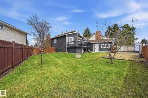 Expansive backyard featuring a manicured lawn, full-height privacy fencing, and a built-in fire pit - 1729 65 Street, Edmonton, AB - Outdoor