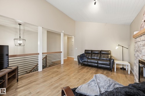 Spacious living area featuring vaulted ceilings with wood-plank finish, light wood-finish flooring, and a stone-clad fireplace - 1729 65 Street, Edmonton, AB - Indoor Photo Showing Other Room With Fireplace